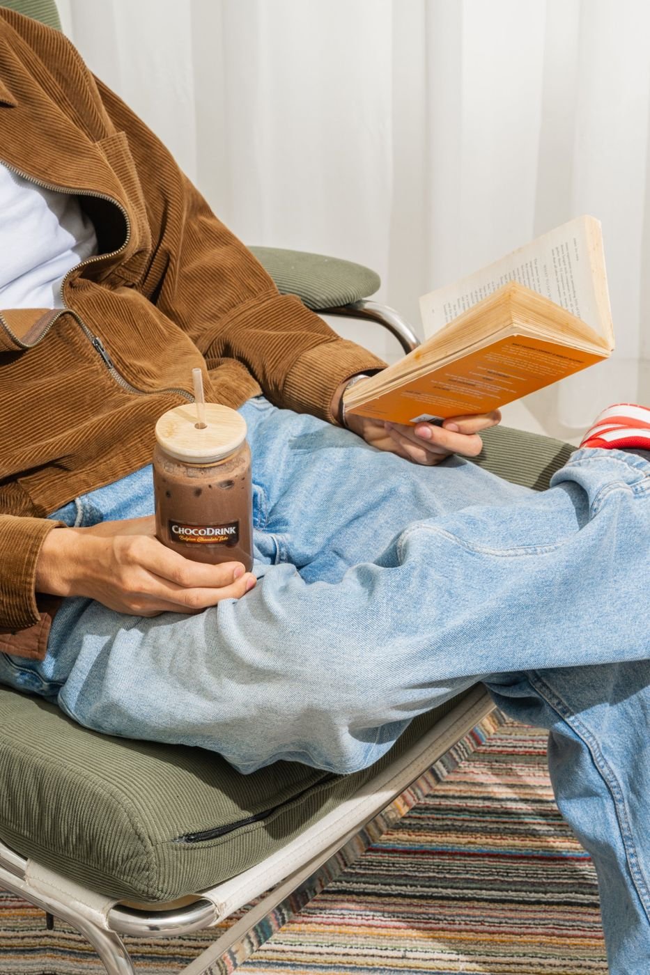 Person reading in a lounge chair holding an iced ChocoDrink