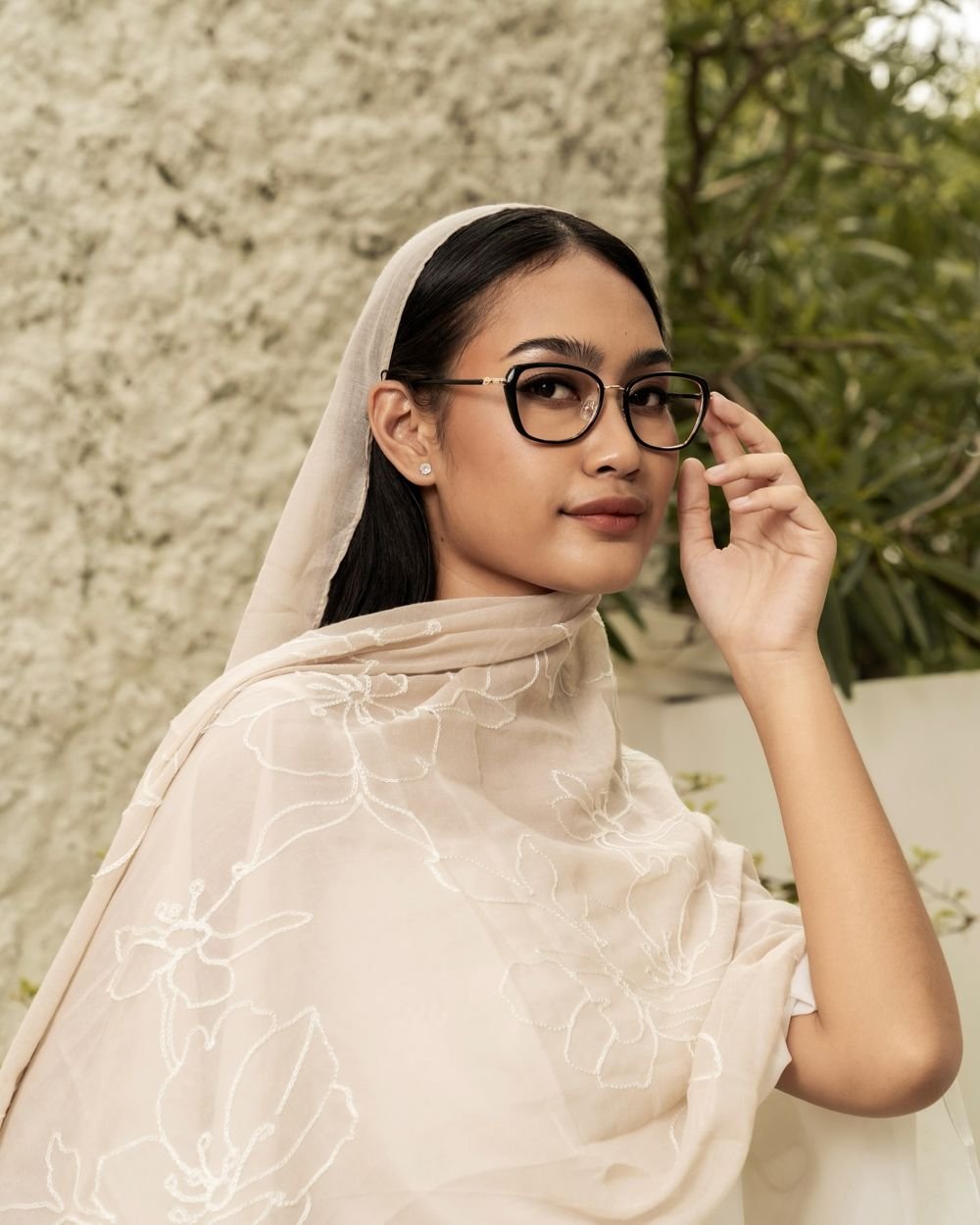 Woman in an embroidered scarf adjusting black frames