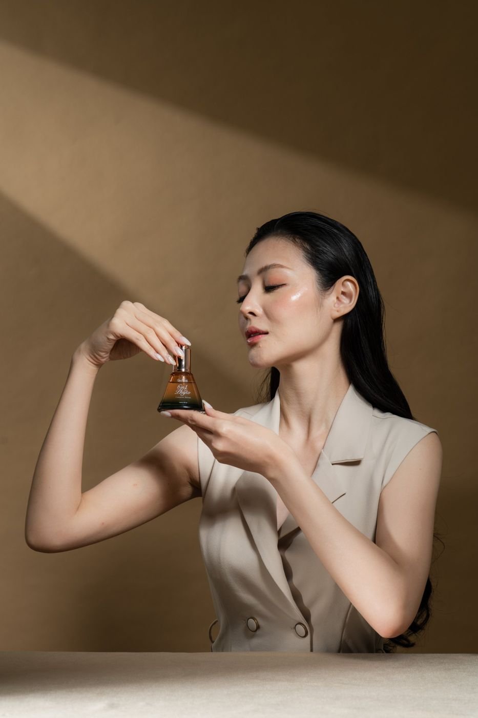Model holding the GlowMerald 6in1 Phyto serum in warm light